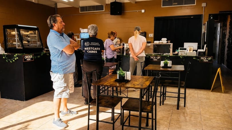 Customers ordering and picking up food at a casual restaurant counter with high-top tables.